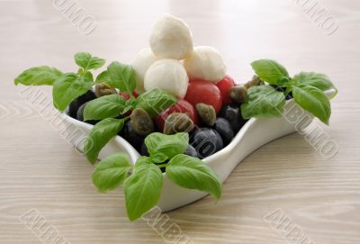 Appetizer of mozzarella, cherry tomatoes and olives and basil
