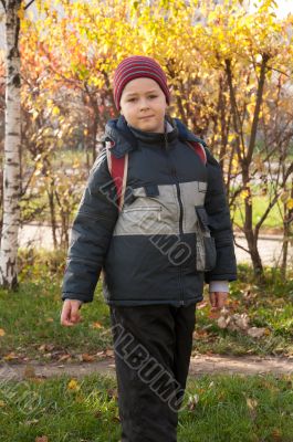 A boy with a backpack in the autumn City Park