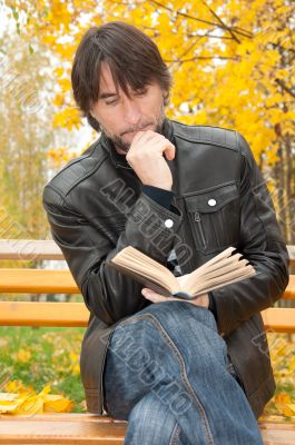 Middle-aged man with a book in autumn park