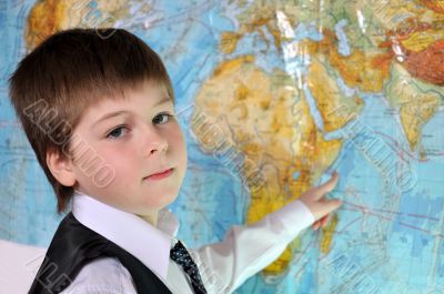 The boy is studying the physical map of the world