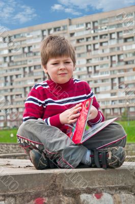 A boy with a book in city park