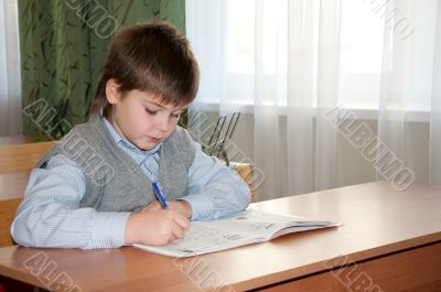 Schoolboy at his desk in the classroom makes the lessons