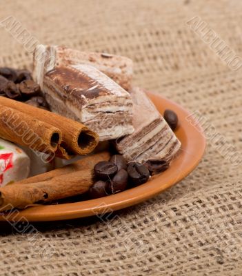 Sweets, cinnamon, nuts and coffee beans on a saucer, on burlap b