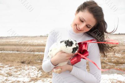 A woman holds a rabbit in her arms and smiles