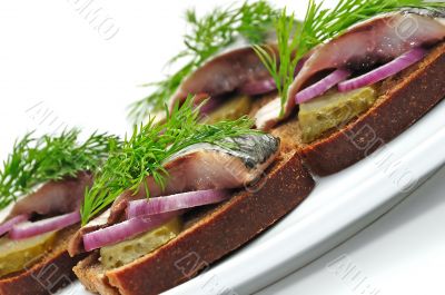 Sandwiches of rye bread with herring, onions and herbs.