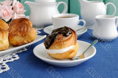 Ã‰clair with chocolate frosting on a plate with a cup of coffee