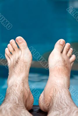 men`s feet on the background of the pool