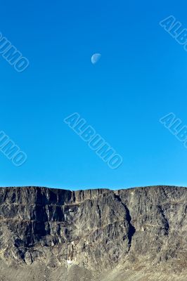 Moon on a background of blue sky and mountains