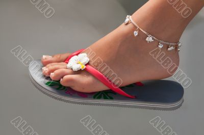 Women`s leg with a bracelet in thong