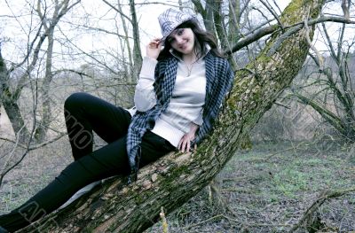 The woman lies on a tree in a hat and scarf