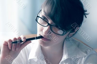 A woman holds a pen in his mouth and listen