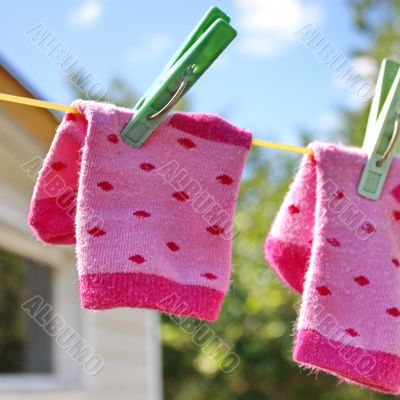 Pink baby sock hanging on the clothesline Pink baby sock hanging on the clothesline