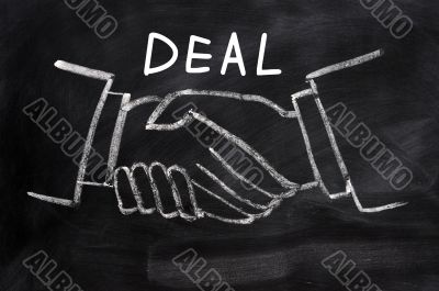 Business deal written on a blackboard background with handshaking