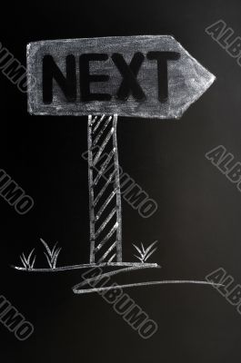 Signpost of next drawn in chalk on a blackboard