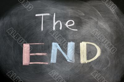 The end - handwritten with chalk on a blackboard with eraser smudges 