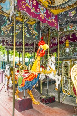 Colorful horses and cock in vintage carousel
