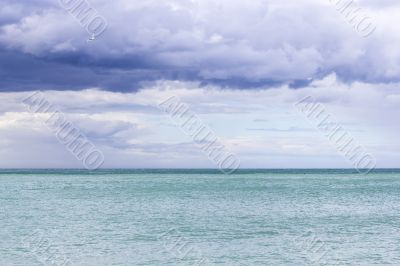 Beautiful azure sea and a gull in the cloudy blue sky