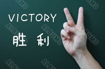 Victory gesture on a blackboard background