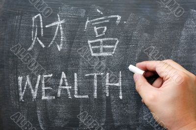 Wealth - word written on a blackboard with a Chinese version