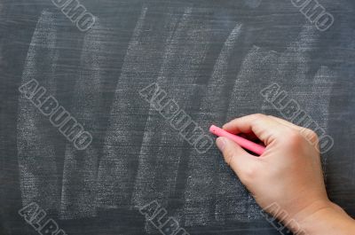 Hand writing on a smudged blank chalkboard with chalk