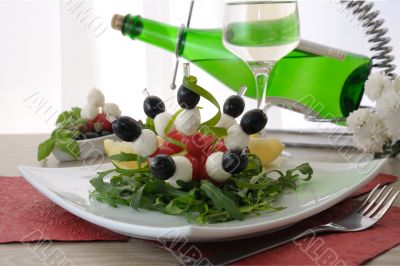 Appetizer of mozzarella, cherry tomatoes and olives with Arugula