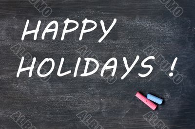 Happy holidays written on a smudged blackboard with chalk