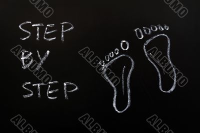 Footprints and the words step by step drawn with chalk