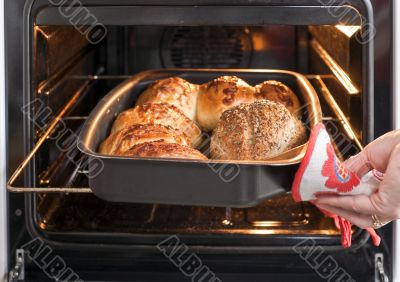 Baker`s hand with bread in oven