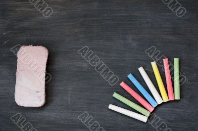 Colorful chalk and eraser on a blank smudged blackboard