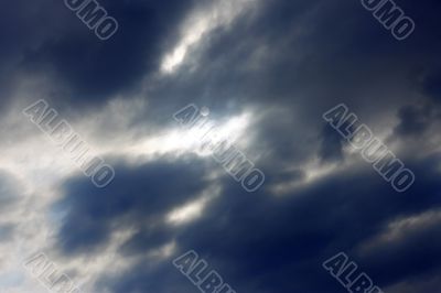 Blue sky and heavy clouds and the sun behind