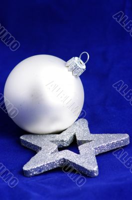 A silver christmas ball and silver christmas star on a blue back