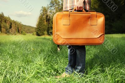 Man with travel bag standing on green lawn Man with travel bag standing on green lawn