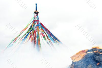 Tibetan prayer flags and mani rock in the smoke