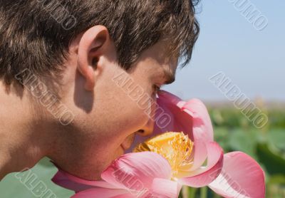 Young man smelling a pink lotus Young man smelling a pink lotus