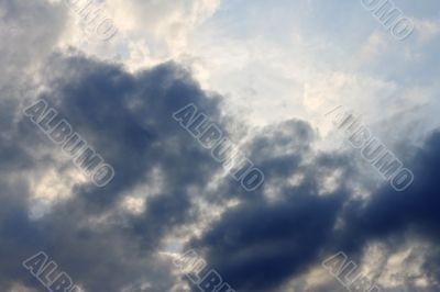 Blue sky and heavy clouds and the sun behind