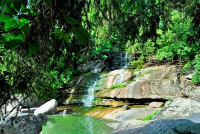 A small waterfall with rocks and green trees