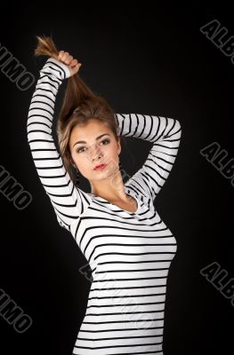 Beautiful girl in a striped dress pulls his hair