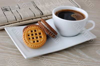 A cup of coffee and biscuits and a newspaper