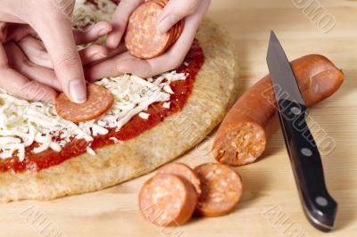 placing slice sausage on a pizza