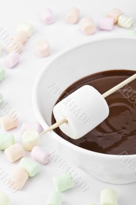 white marshmallow on stick above the melted chocolate bowl