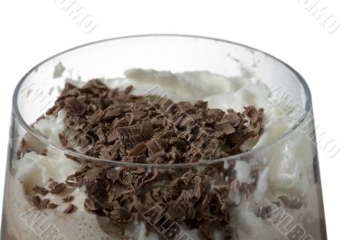 a glass of chocolate milk drink with cream and chocolate bits