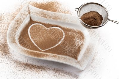 strainer with cocoa while heart shape on a white container