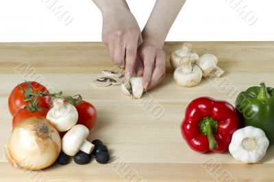 female hand slicing a mushroom for pizza