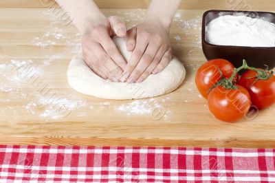 hand flattening the pizza dough