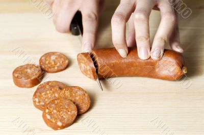 human hand cutting a sausage