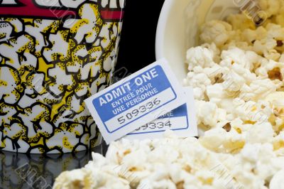 a bucket with a spilled popcorn and movie tickets on the side 