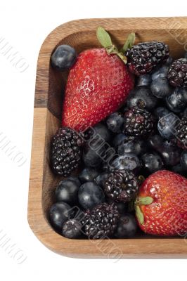 strawberries blueberries and blackberries in wooden bowl