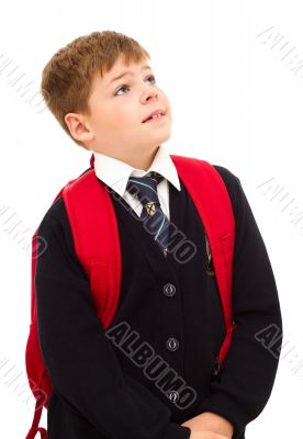 School boy standing and looking up with his backpack.