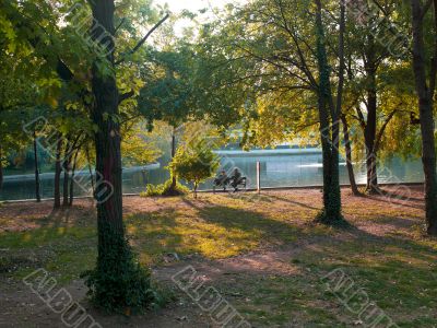 view of two people sitting on bench beside lake