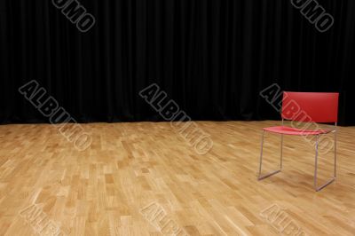A directors chair on a stage with a blackcurtain in background
